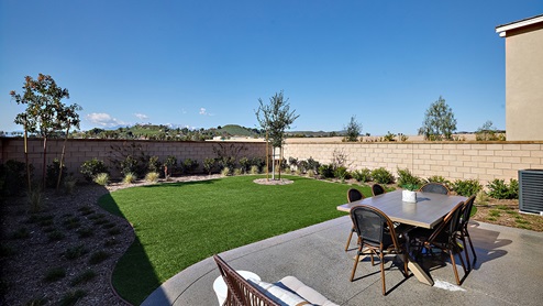 Spacious open-concept backyard with patio area and turf