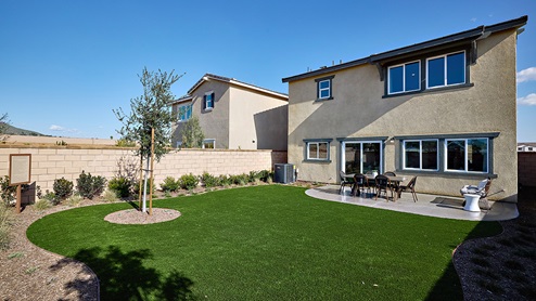 Spacious open-concept backyard with patio area and turf