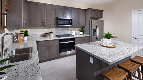 Open-concept kitchen area with dark cabinets and granite countertops