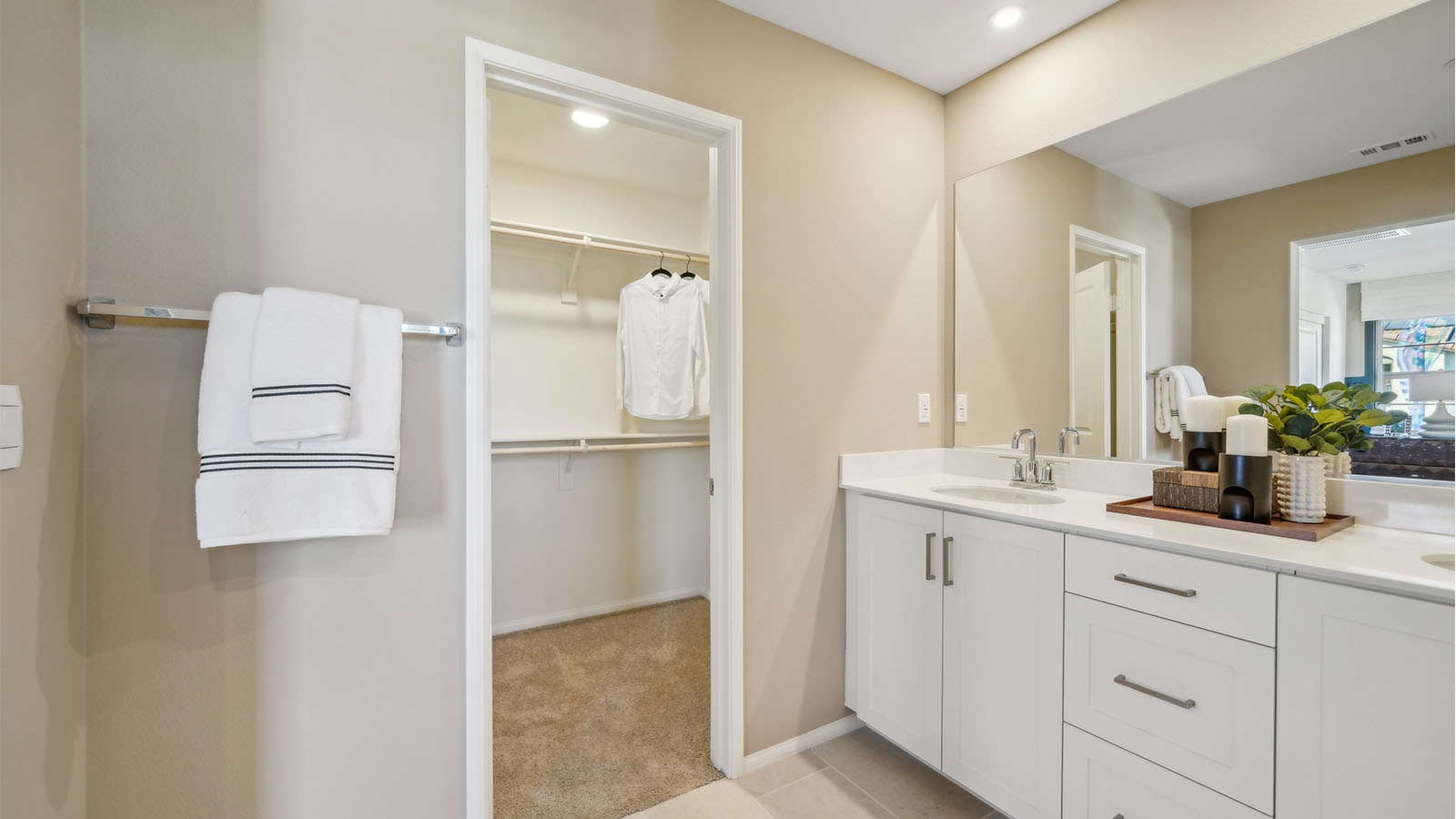 Primary bathroom with white cabinets and countertops with dual sinks and shower