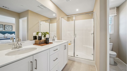 Primary bathroom with white cabinets and countertops with dual sinks and shower