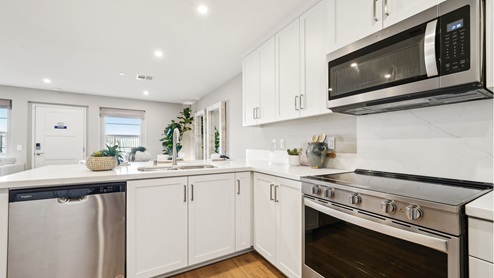 Modern open-concept kitchen with white cabinets and stainless steel applia