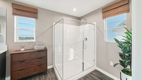 Spacious primary bathroom with laminate flooring and shower