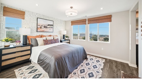 Primary bedroom with king bed, accent wall, and laminate flooring