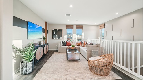 Spacious upstairs loft area with couches, entrainment center, and tv with laminate flooring