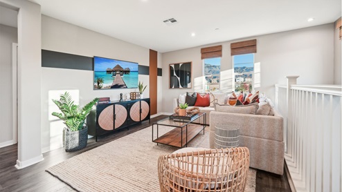 Spacious upstairs loft area with couches, entrainment center, and tv with laminate flooring