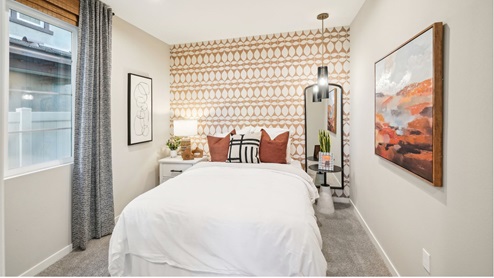 Secondary bedroom with wallpaper accent wall and plush carpet