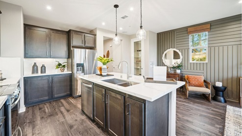 Modern open-concept kitchen with brown cabinets and quartz countertops with stainless steel appliances