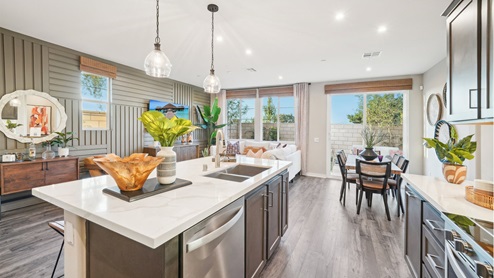 Modern open-concept kitchen with brown cabinets and quartz countertops with stainless steel appliances