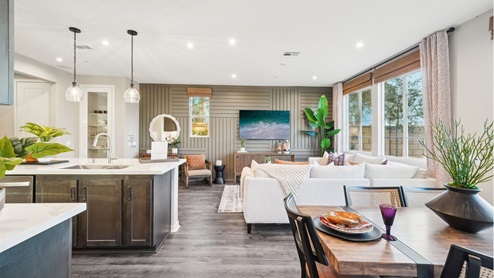 Spacious open-concept dining, great room, and kitchen with brown accents and laminate flooring