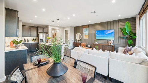 Spacious open-concept dining, great room, and kitchen with brown accents and laminate flooring