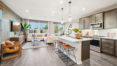 Modern open-concept kitchen with brown cabinets and quartz countertops with stainless steel appliances
