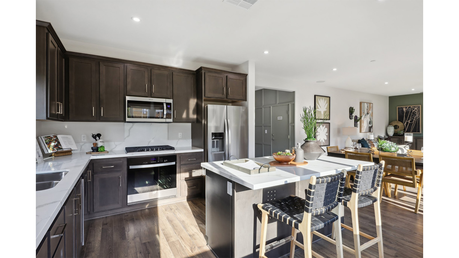 Open kitchen with dark cabinets quartz countertops and stainless steel appliances