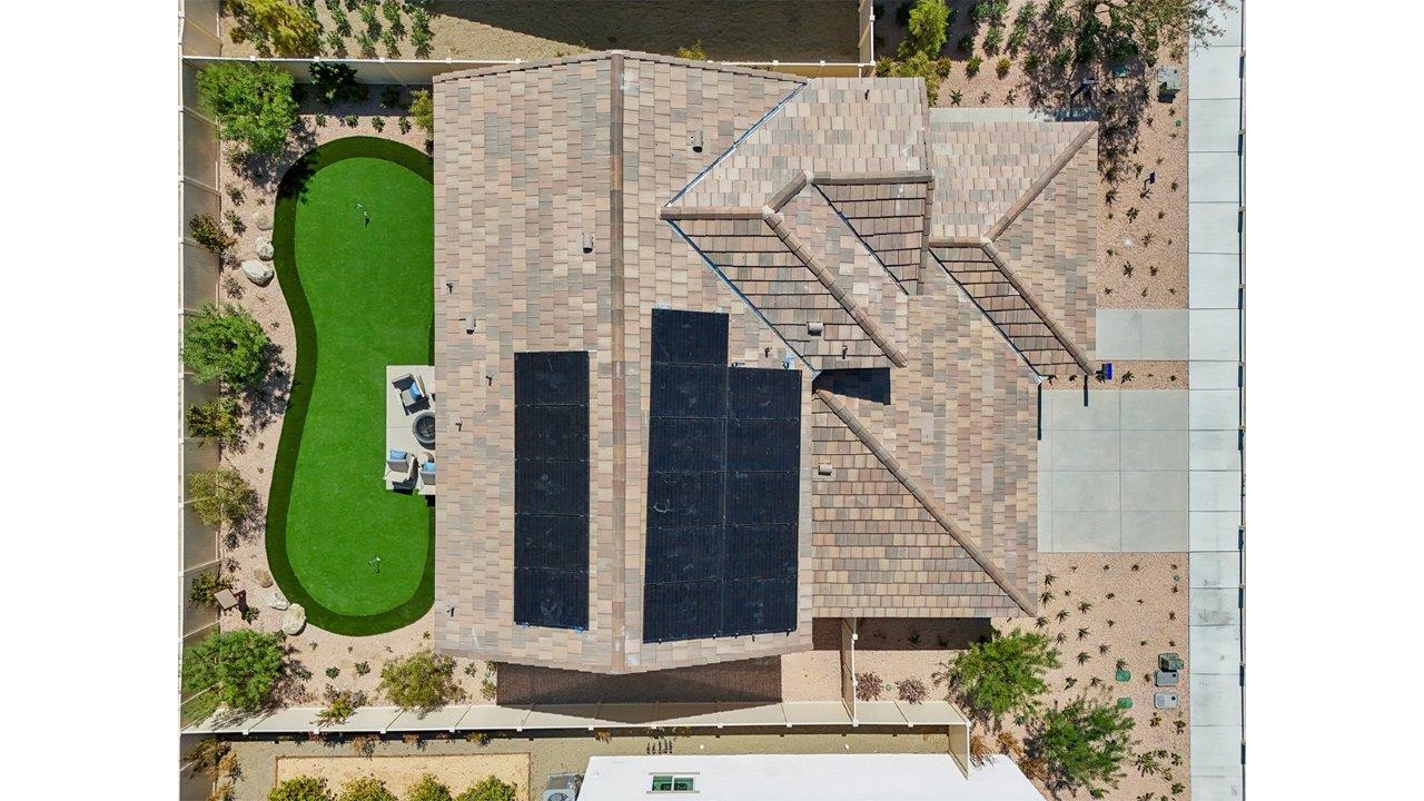 Aerial photo of home with solar panels and turf backyard