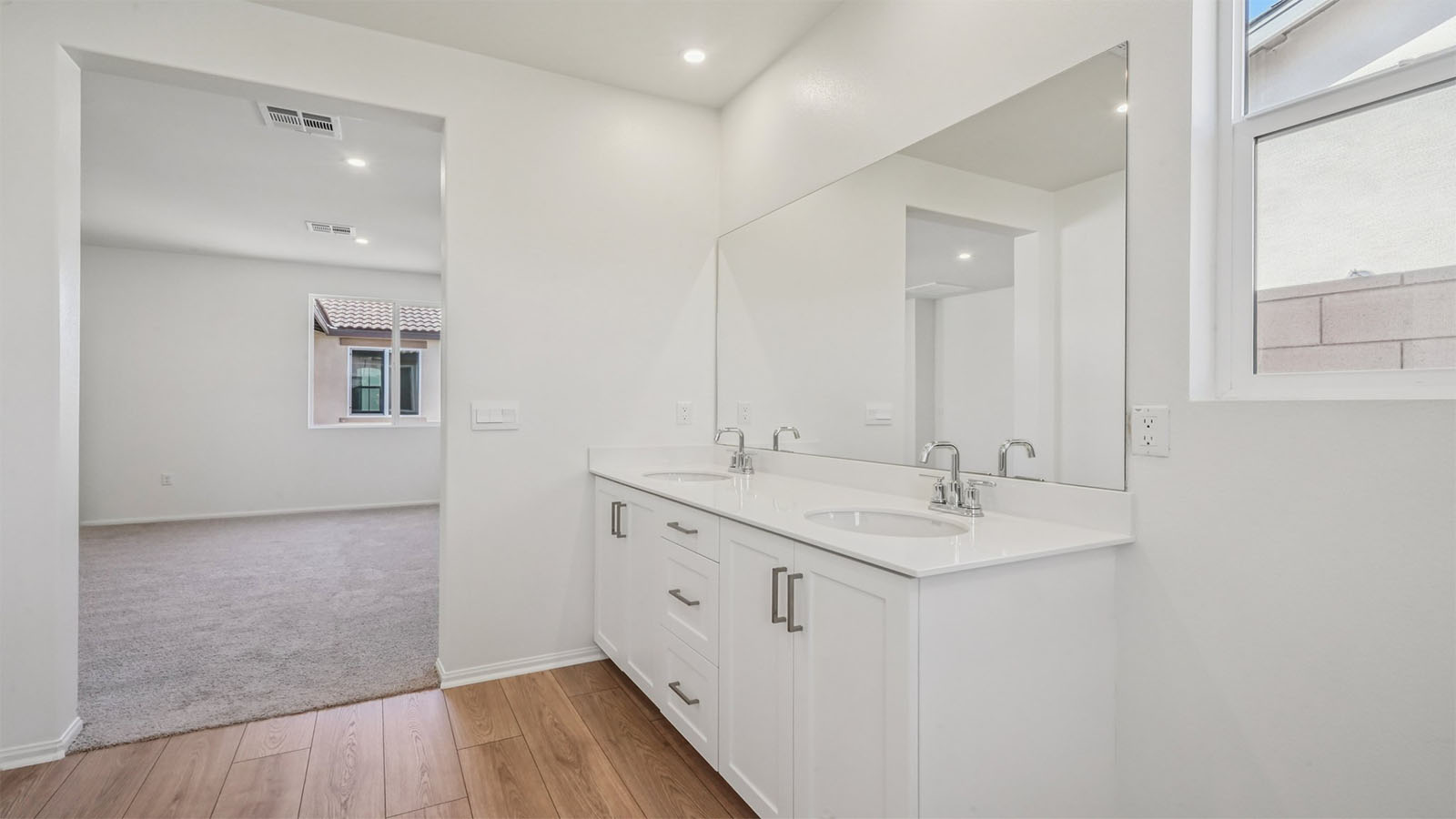 Primary bathroom with dual vanities and walk-in closet