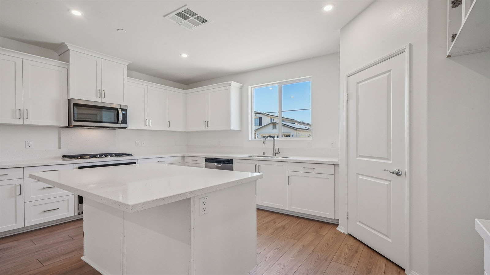 Modern kitchen with white cabinets quartz countertops and stainless steel appliances