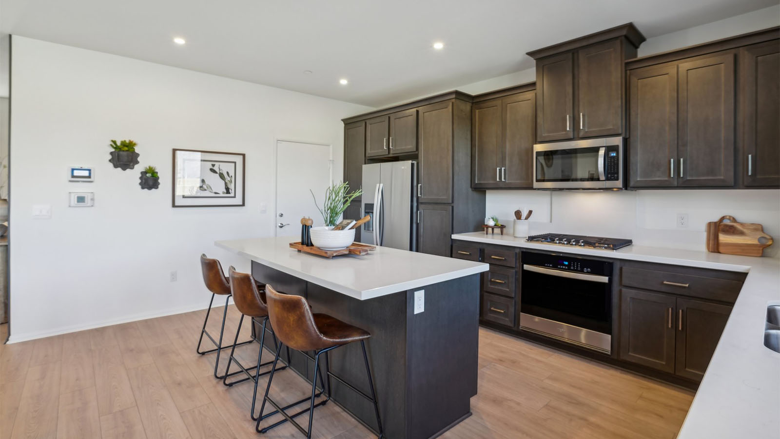 Open kitchen with dark cabinets quartz countertops and stainless steel appliances