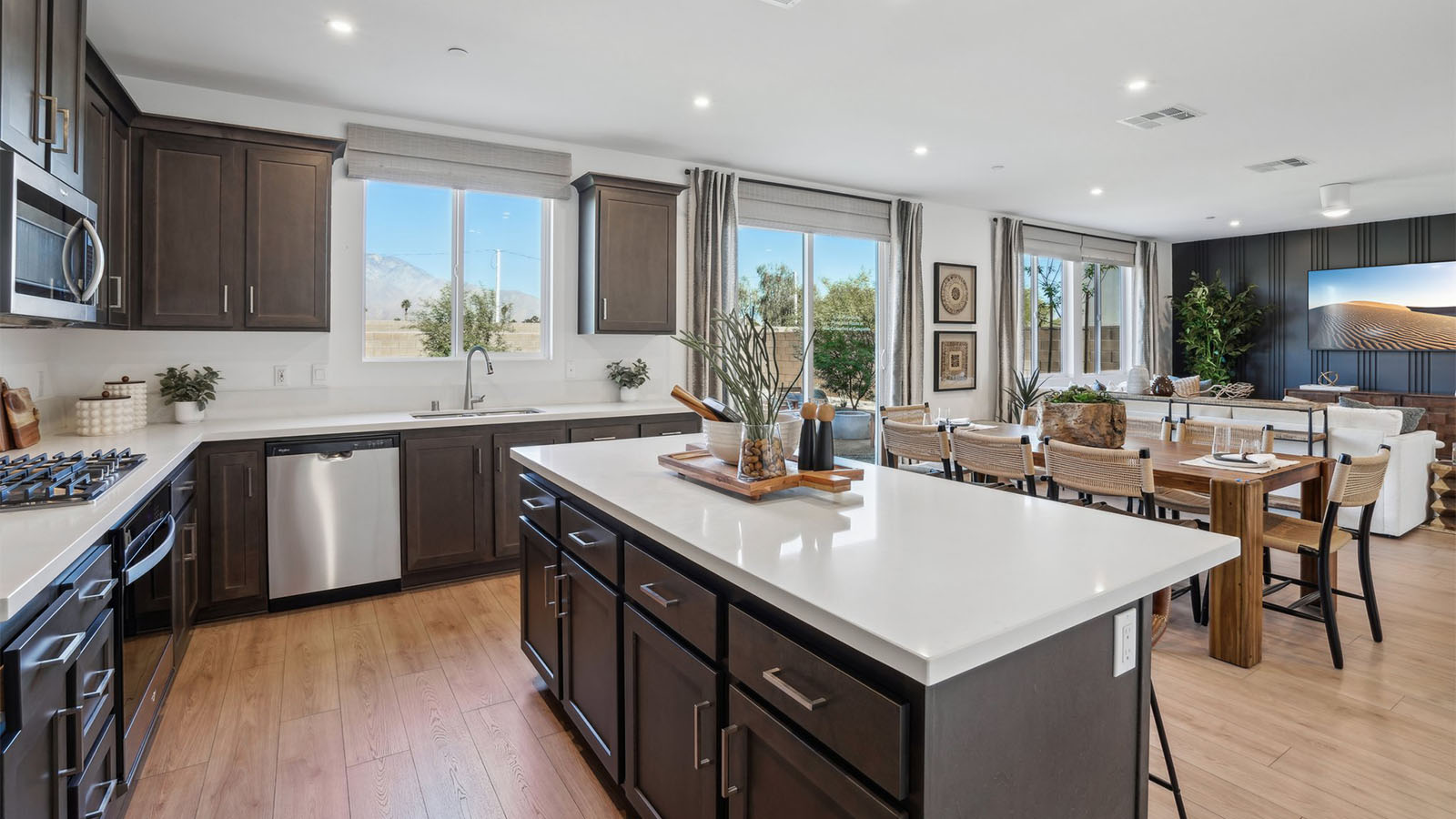 Open kitchen with dark cabinets quartz countertops and stainless steel appliances
