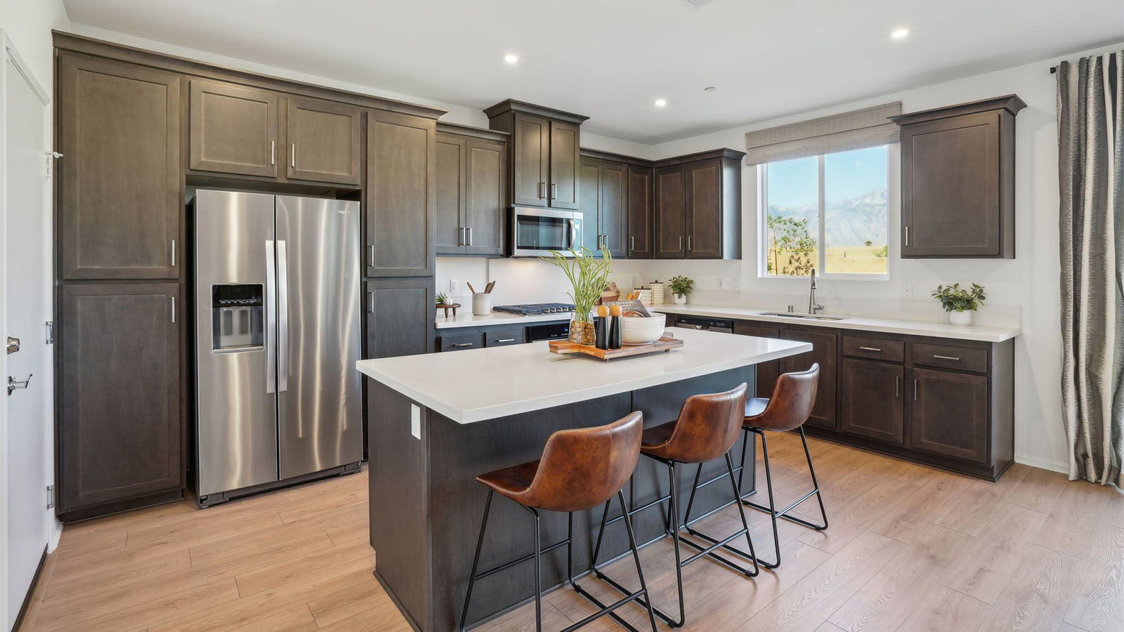 Open kitchen with dark cabinets quartz countertops and stainless steel appliances