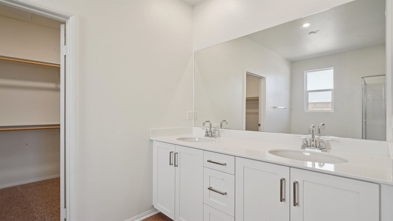 Primary bathroom with dual vanities and walk-in closet