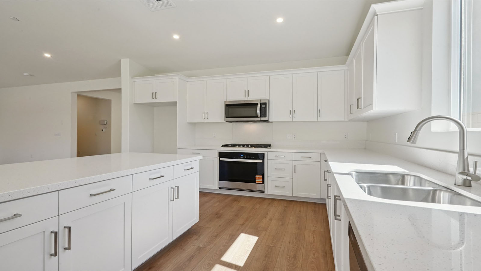 Modern kitchen with white cabinets quartz countertops and stainless steel appliances