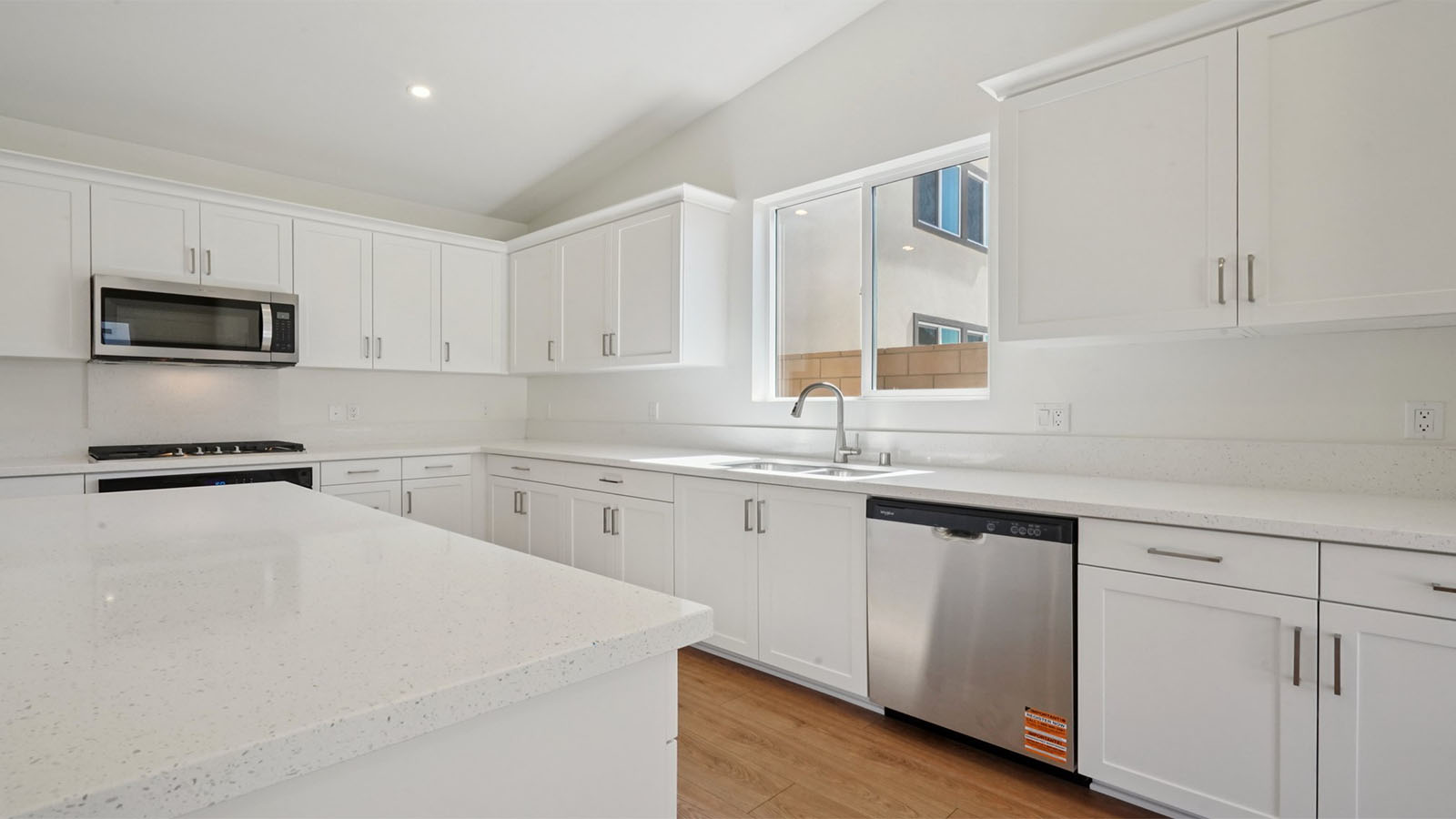 Modern kitchen with white cabinets quartz countertops and stainless steel appliances