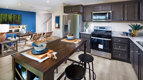 Open-concept kitchen area with dark cabinets and stainless steel appliances