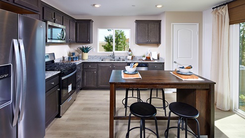 Open-concept kitchen area with dark cabinets and stainless steel appliances