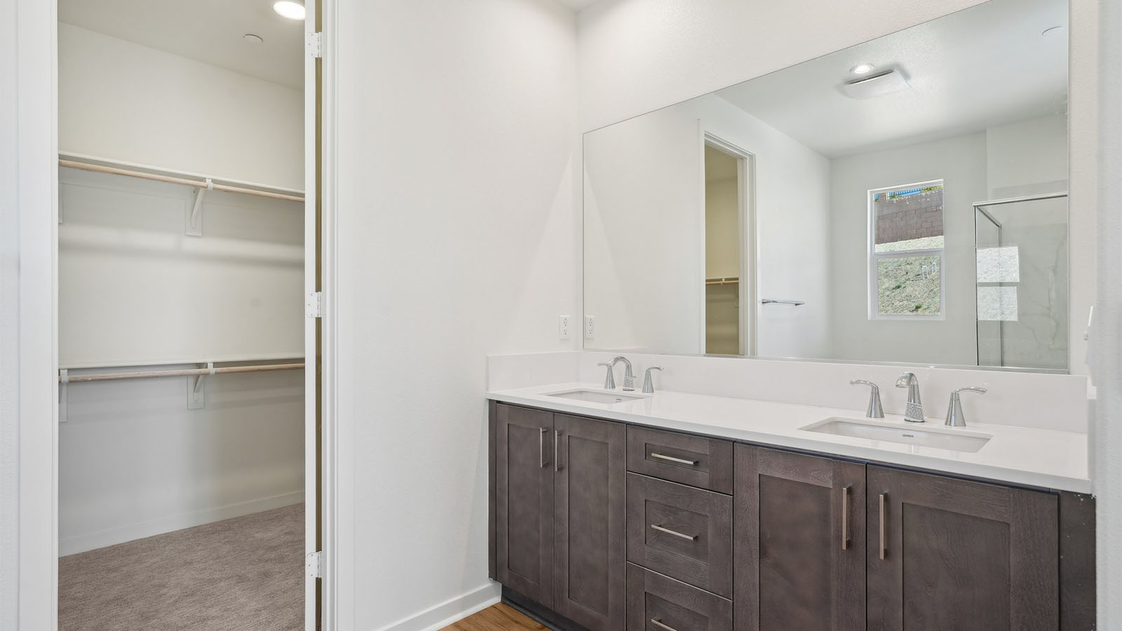 Primary bathroom with dual vanities and walk-in closet