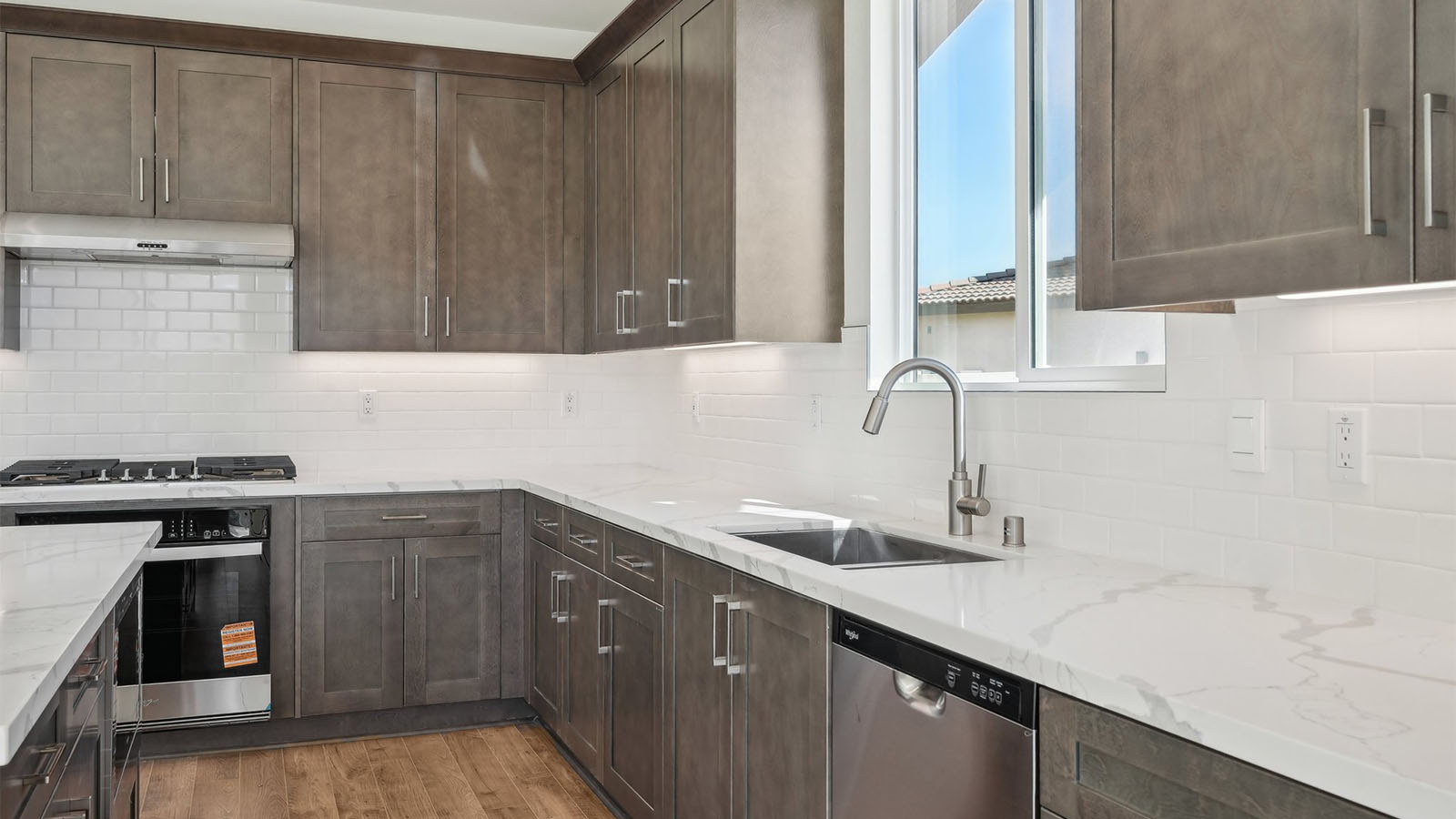 Open kitchen with dark cabinets quartz countertops and stainless steel appliances
