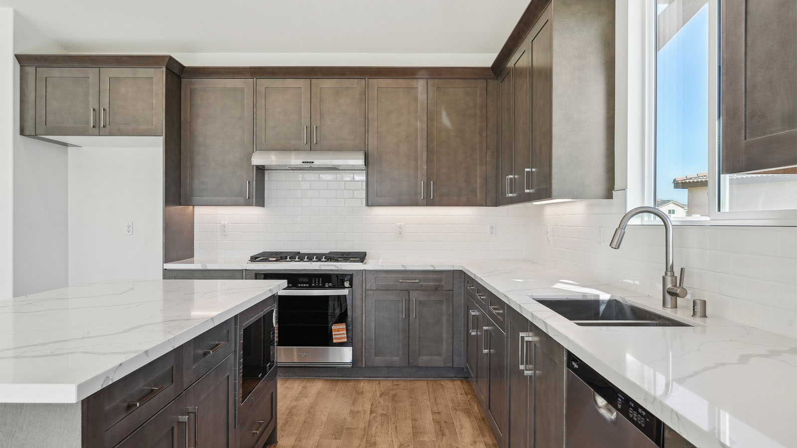 Open kitchen with dark cabinets quartz countertops and stainless steel appliances