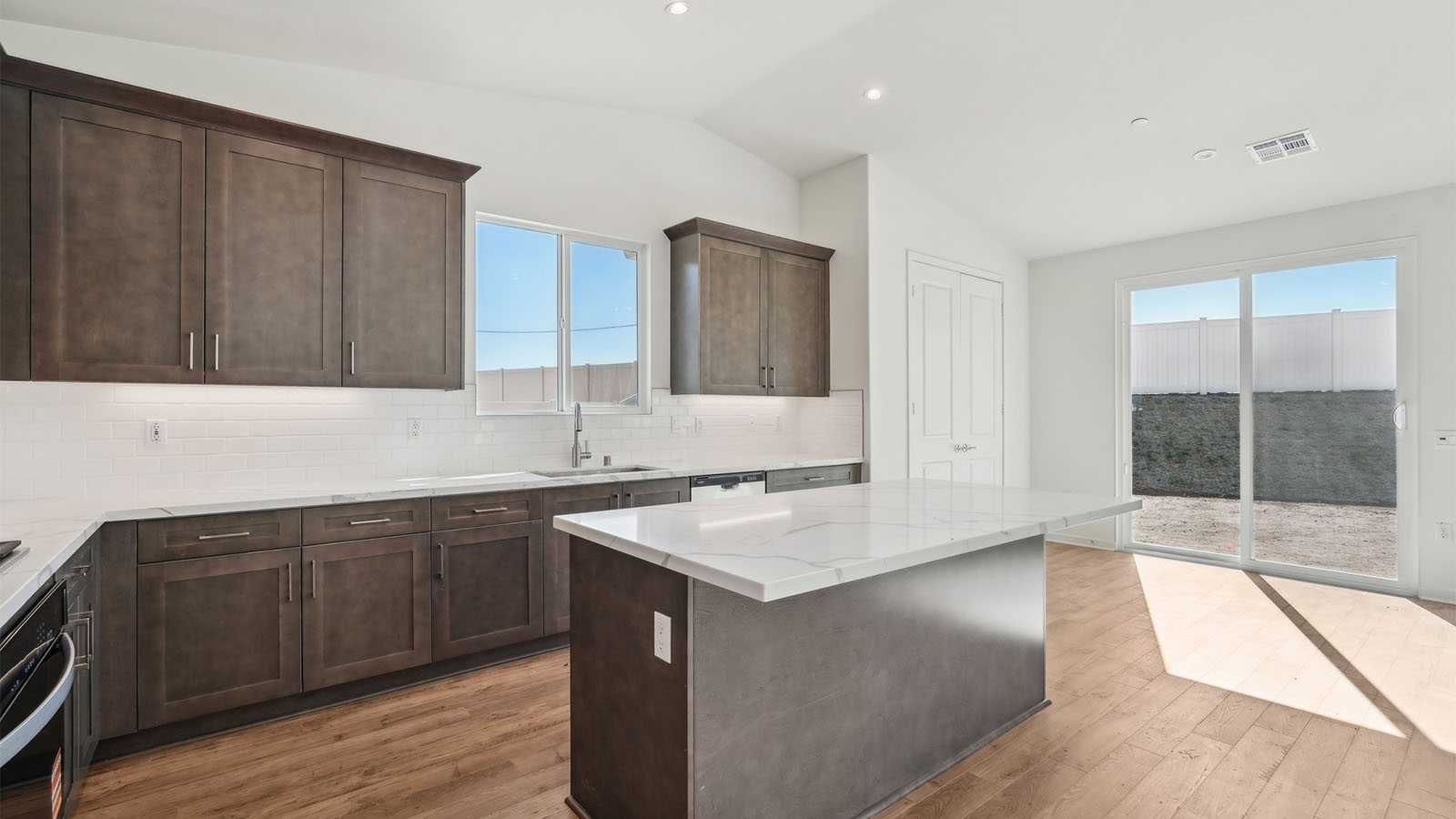 Open kitchen with dark cabinets quartz countertops and stainless steel appliances