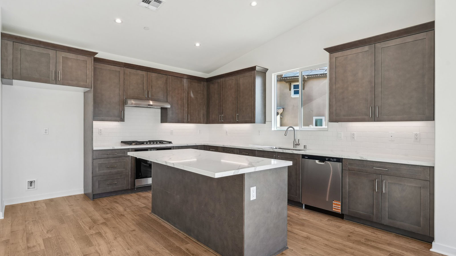 Open kitchen with dark cabinets quartz countertops and stainless steel appliances