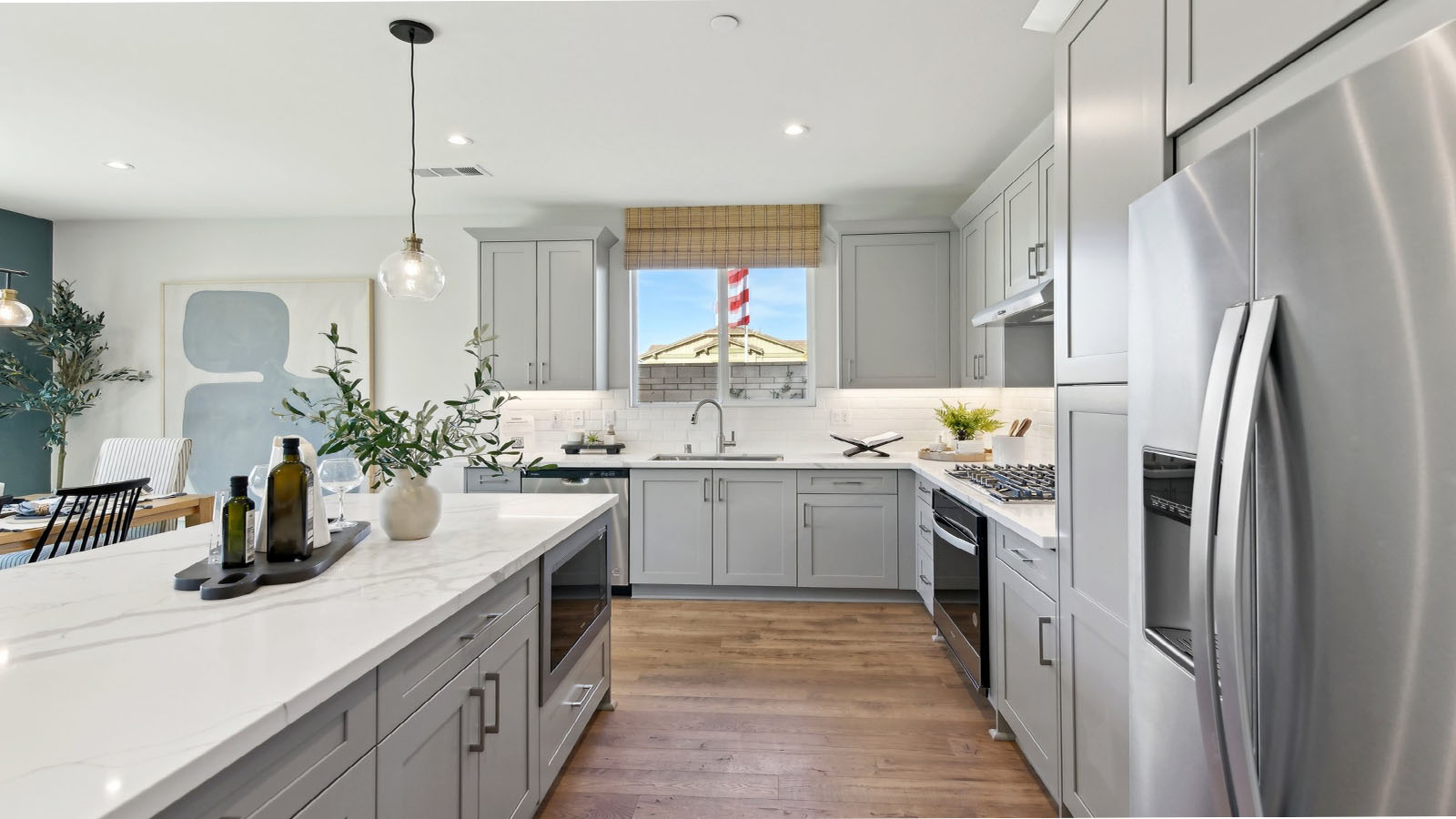 Modern kitchen with light grey cabinets quartz countertops and stainless steel appliances
