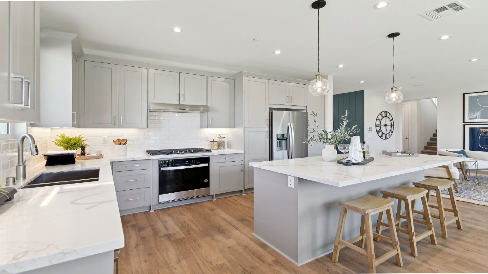 Modern kitchen with light grey cabinets quartz countertops and stainless steel appliances