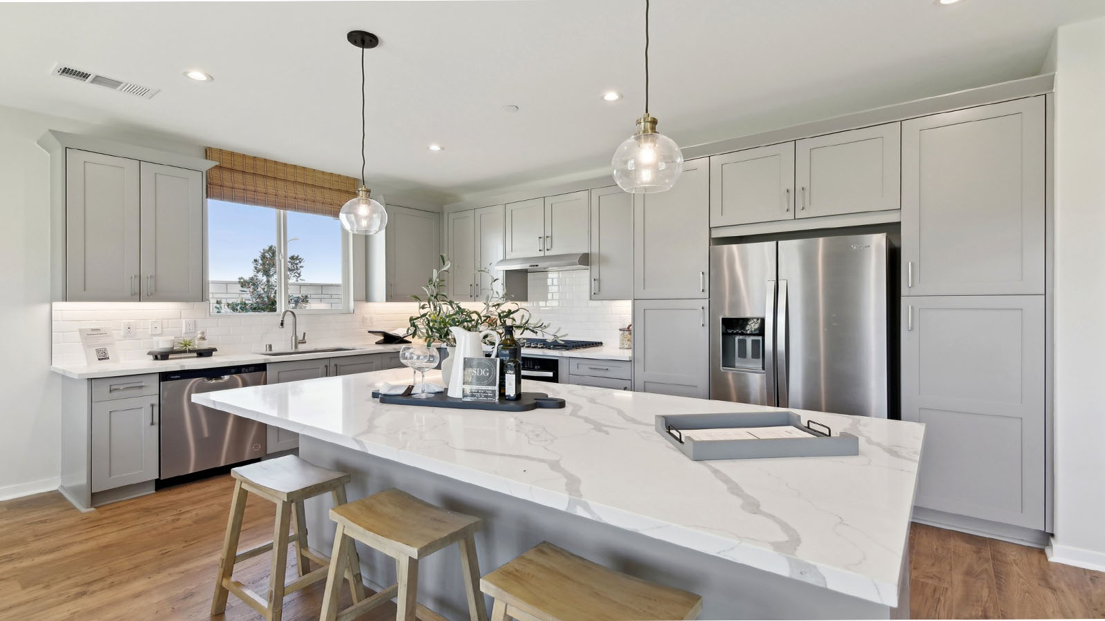 Modern kitchen with light grey cabinets quartz countertops and stainless steel appliances
