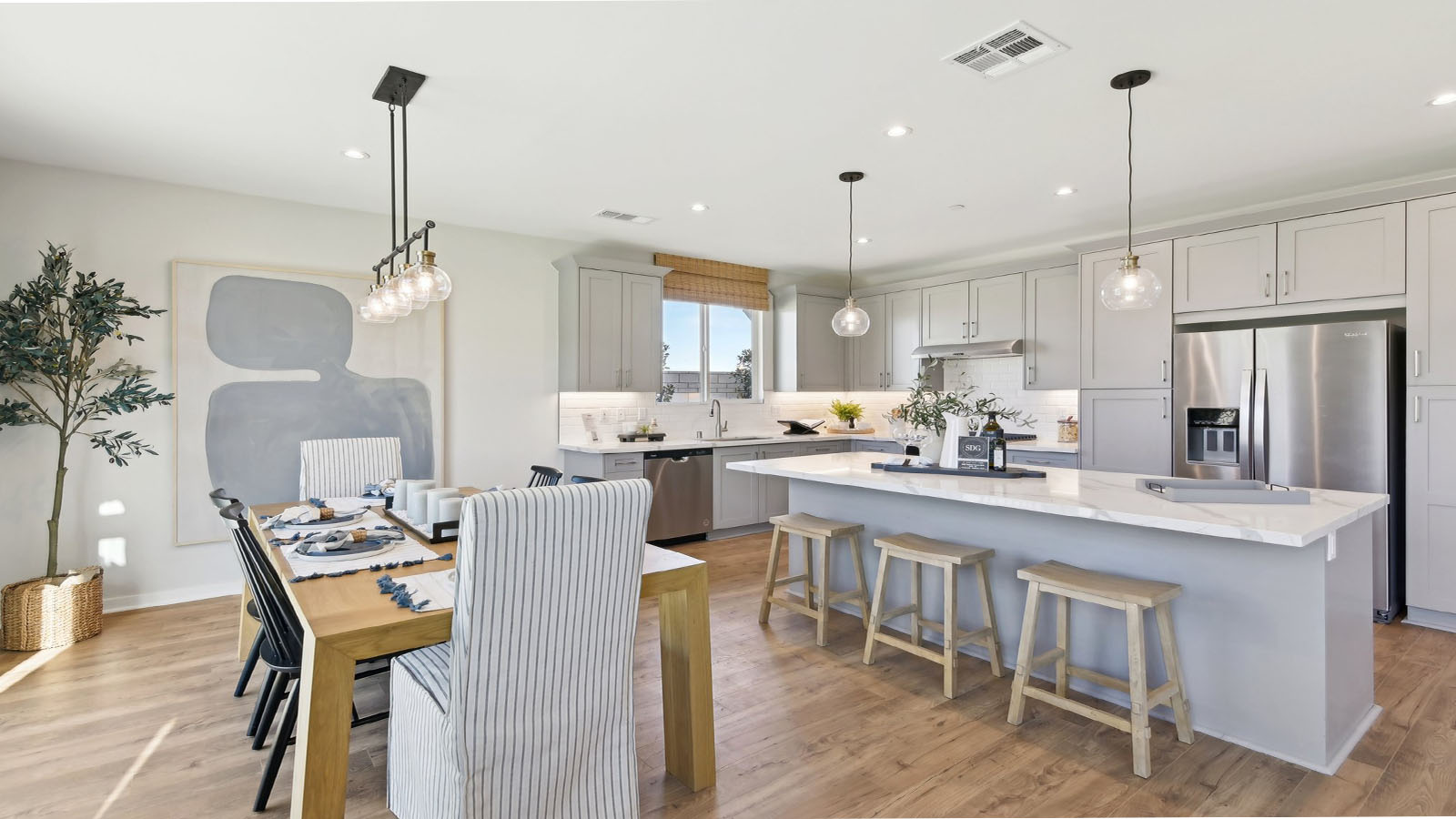 Modern kitchen with light grey cabinets quartz countertops and stainless steel appliances and dining area