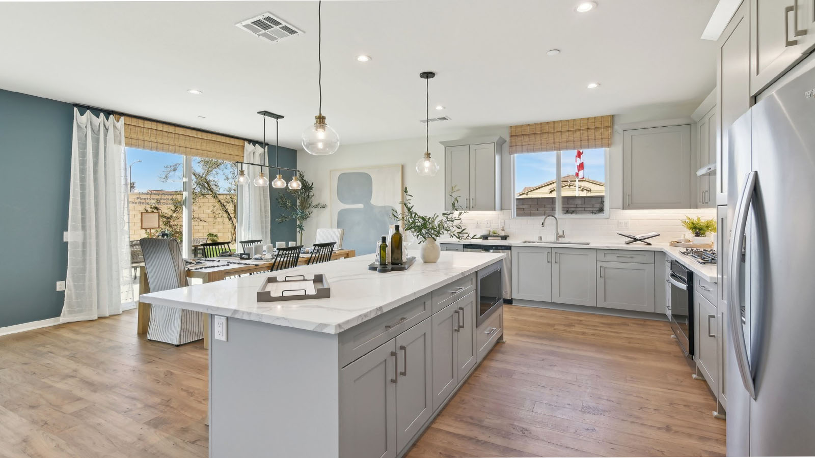 Modern kitchen with light grey cabinets quartz countertops and stainless steel appliances