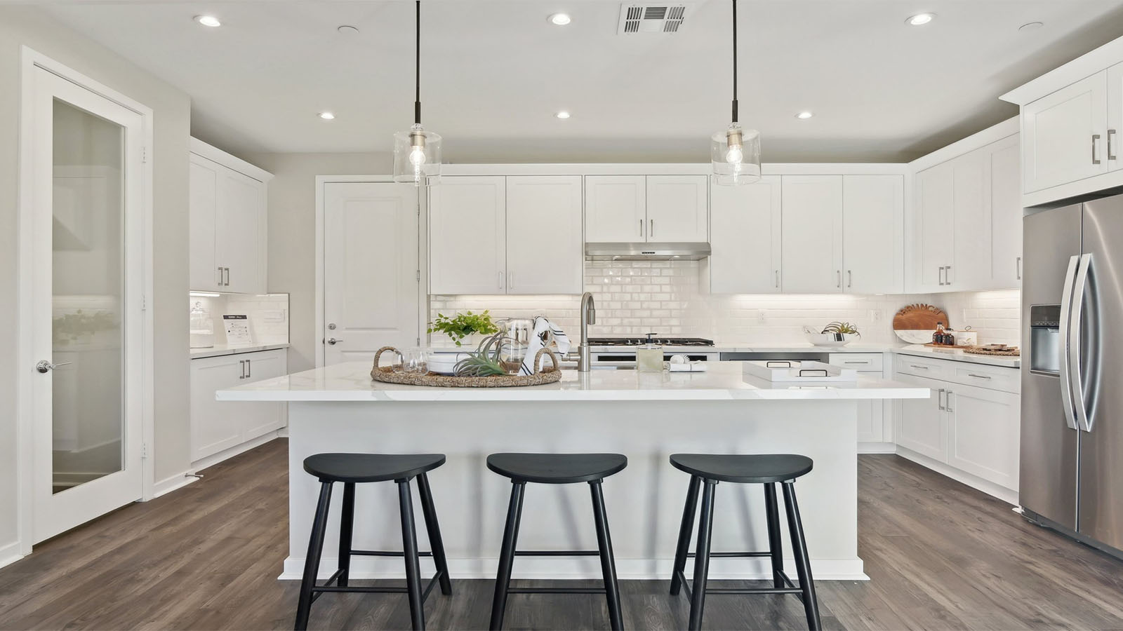 Modern kitchen with white cabinets quartz countertops and stainless steel appliances