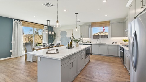 Modern kitchen with light grey cabinets quartz countertops and stainless steel appliances and dining area with slider to rear yard