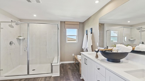 Primary bathroom with dual vanities and walk-in shower