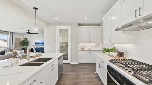 Modern kitchen with white cabinets quartz countertops and stainless steel appliances