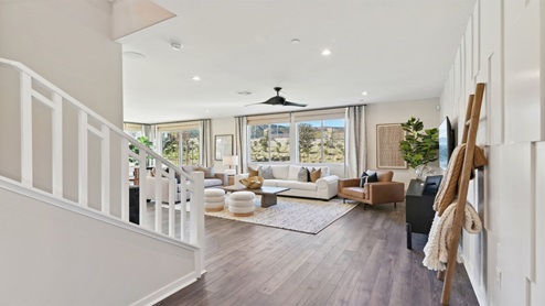 Hallway leading to great room with open railing stairs with white handrail
