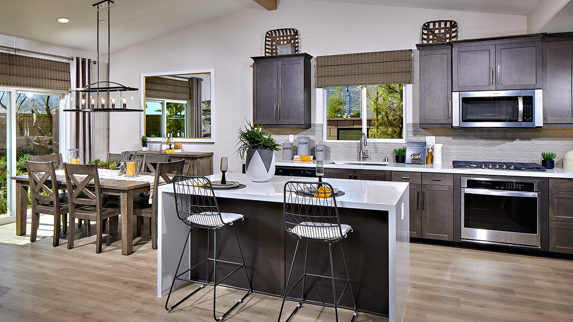 Open concept kitchen with dark cabinets quartz countertops and stainless steel appliances
