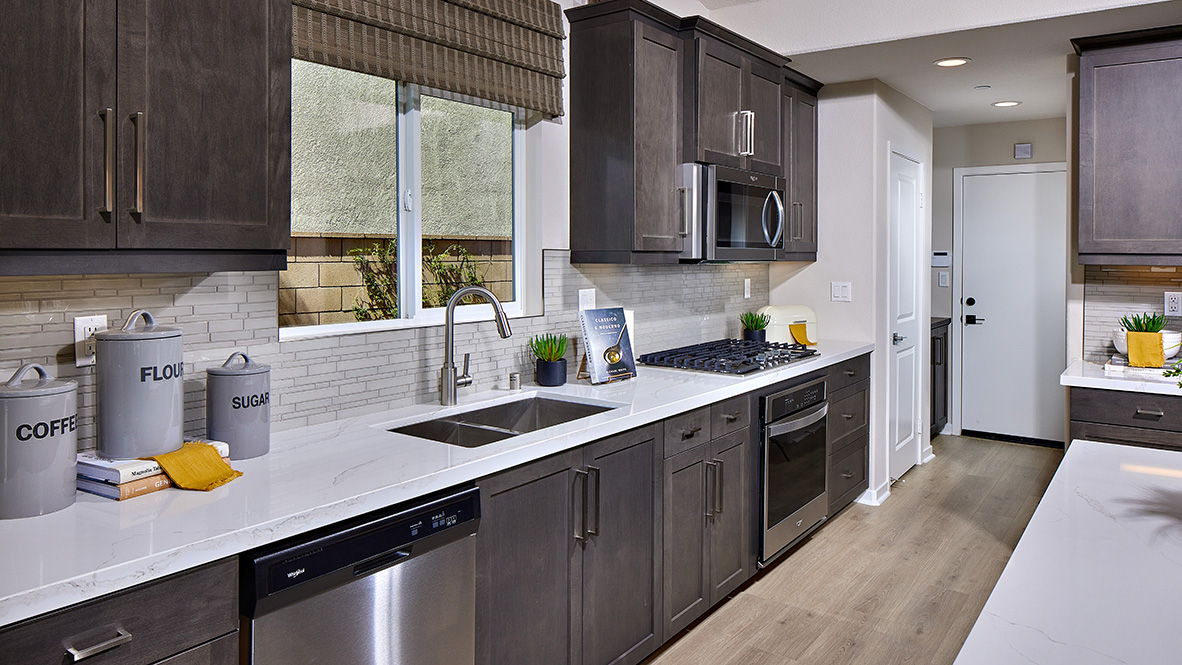 Open concept kitchen with dark cabinets quartz countertops and stainless steel appliances