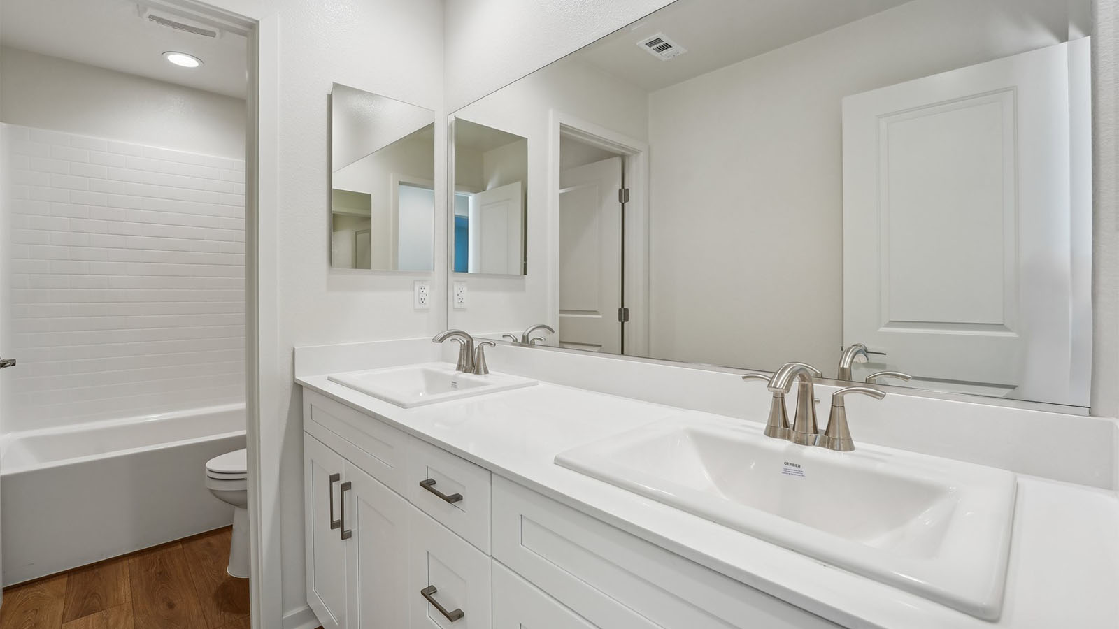 bathroom with separate toilet area and dual vaniteis