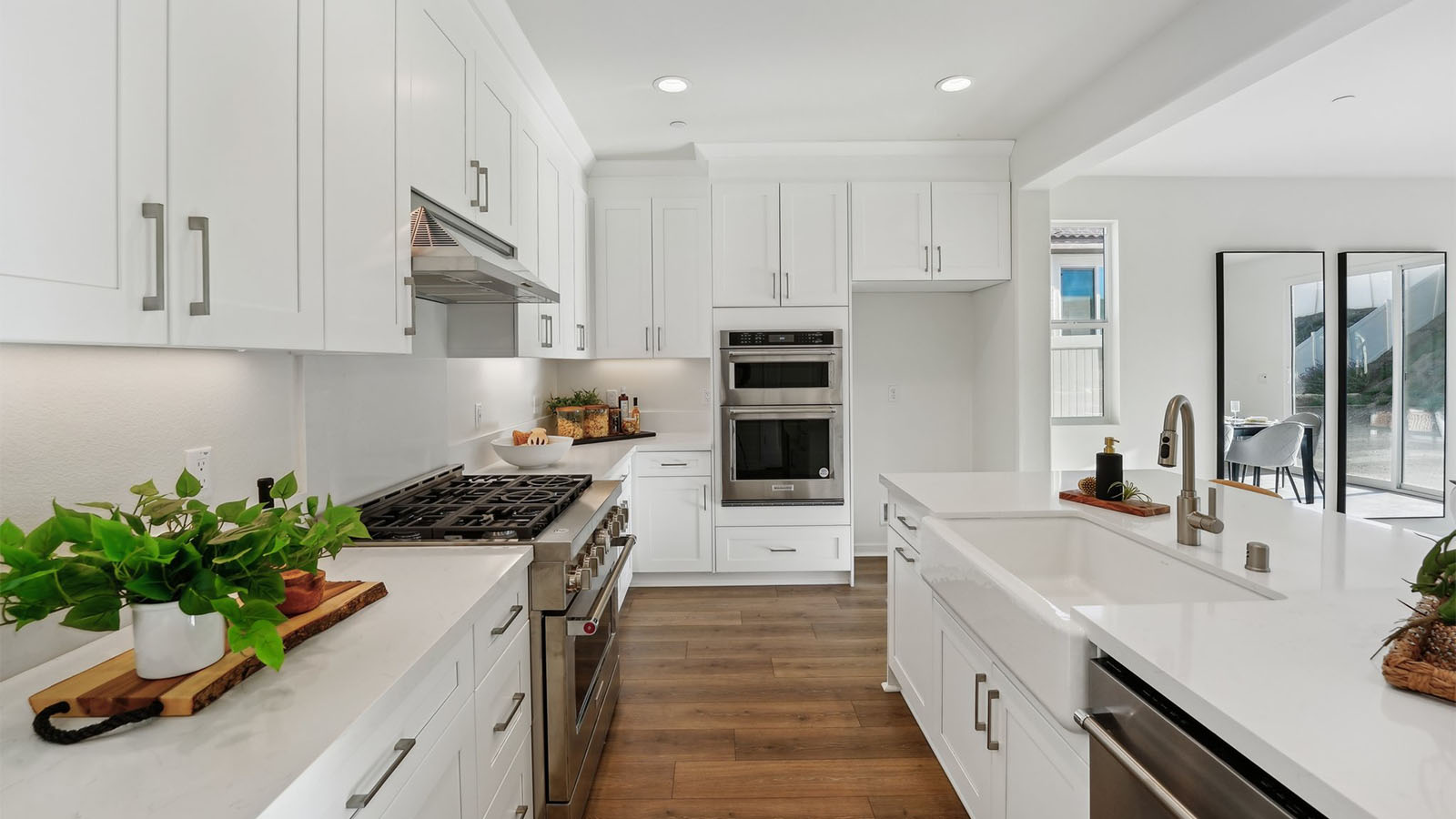 Open concept kitchen with white cabinets quartz countertops and stainless steel appliances
