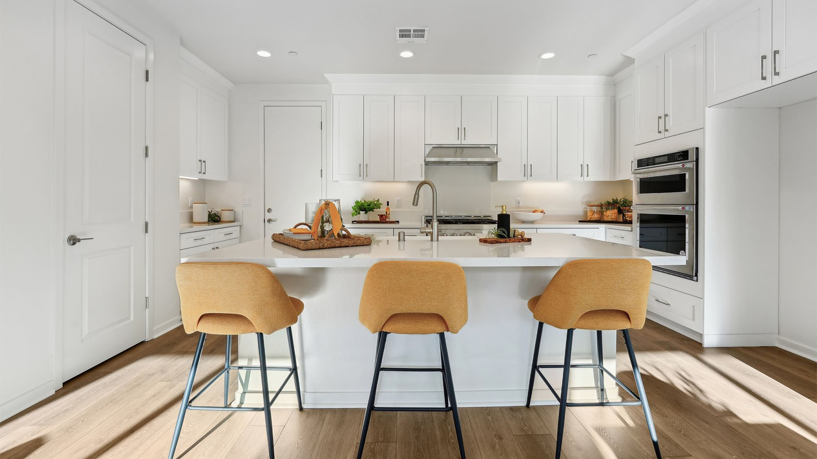Open concept kitchen with white cabinets quartz countertops and stainless steel appliances