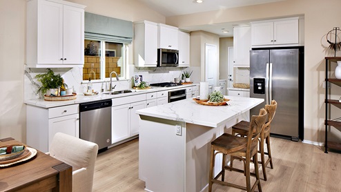 Santolina in Victorville model home kitchen with stainless appliances, white cabinets, and marble countertops