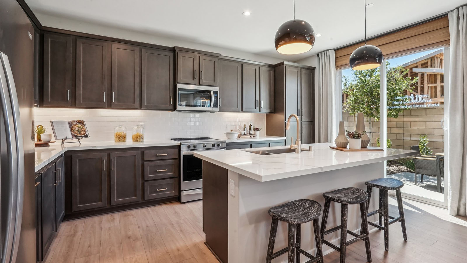 Open kitchen with dark cabinets quartz countertops and stainless steel appliances